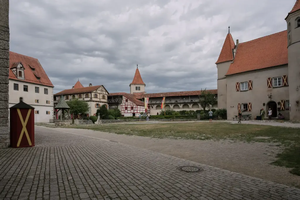 Pflasterweg im Burghof, links und rechts historische Gebäude mit roten Dächern