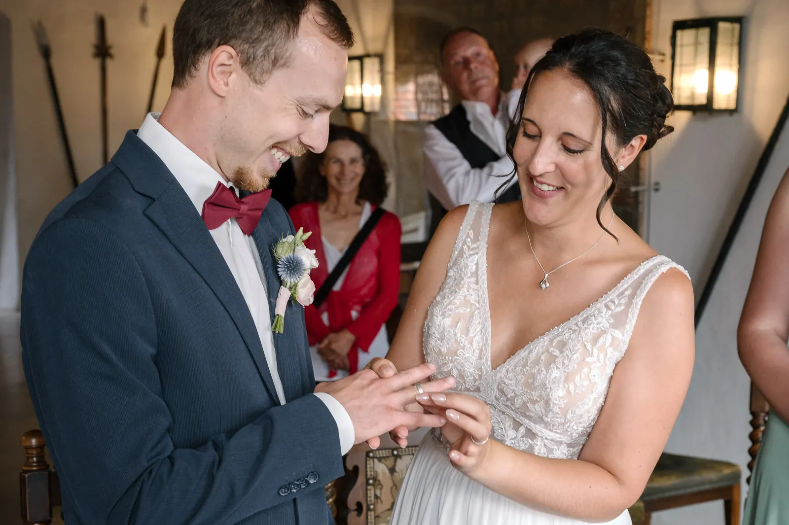 Bräutigam steckt der Braut den Ring an den Finger, beide lachen