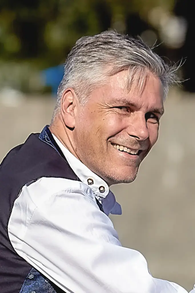 Porträt von Harry Wolfsbauer, der freundlich lächelnd über die Schulter in die Kamera schaut